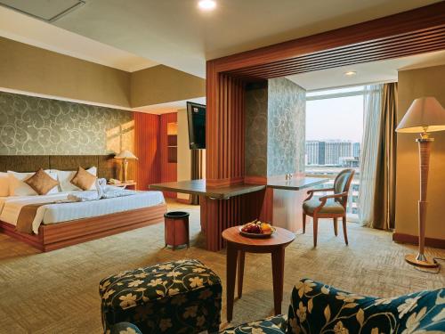 a hotel room with a bed and a table and chairs at Horison Ultima Menteng Jakarta in Jakarta