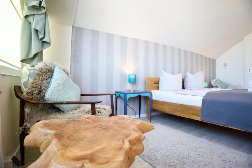 a bedroom with a bed and a chair and a table at Meerblick 60 in Nordstrand