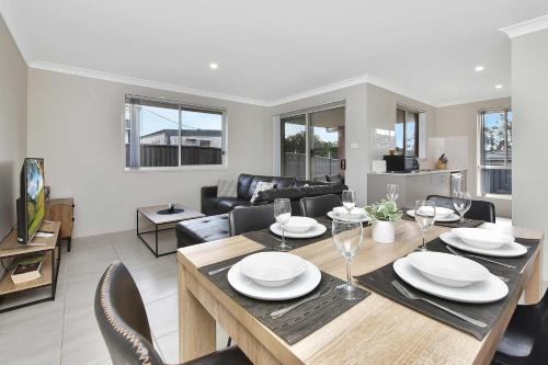 a dining room and living room with a table and chairs at Hunter Hideaway in Cessnock