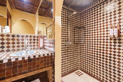 a bathroom with a shower and a sink at Hotel Riad Xaluca in Merzouga