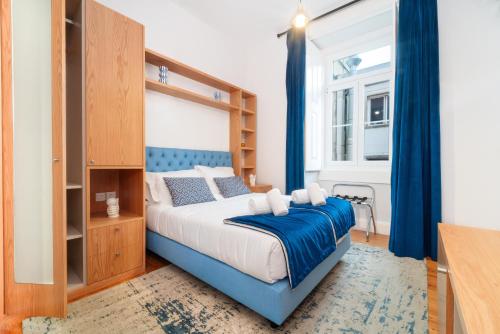 a bedroom with a bed with a blue headboard at A&S Suítes Coimbra in Coimbra