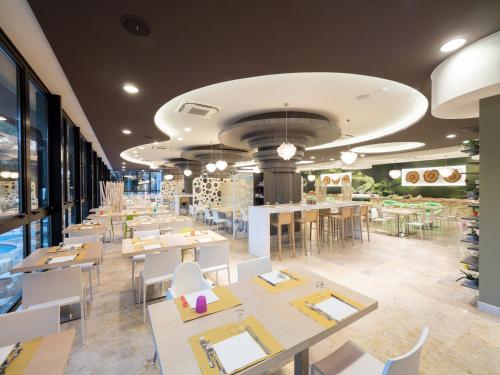 un restaurante con mesas blancas, sillas blancas, mesas y mesa en Meridiana Family & Nature Hotel, en Marina Romea