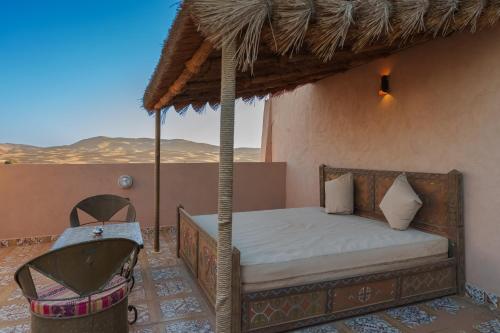 a bed in a room with a view of the desert at Hotel Riad Xaluca in Merzouga