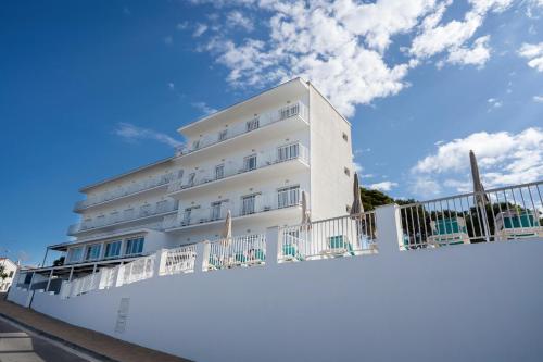 a white building with a fence in front of it at BLUESEA Playa Azul in Cala en Porter