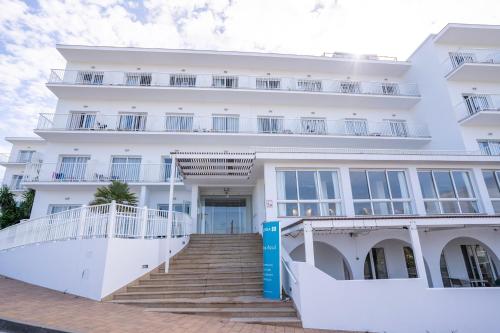 a white building with stairs in front of it at BLUESEA Playa Azul in Cala en Porter