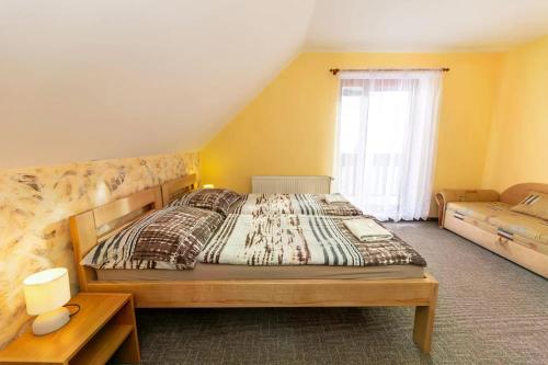 a bedroom with a bed and a couch and a window at Apartmány Šumava in Hojsova Stráž