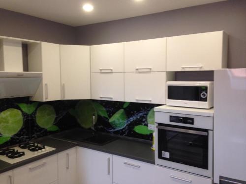 a kitchen with white cabinets and a microwave at Apartment on Nezalezhnosti Embankment in Uzhhorod