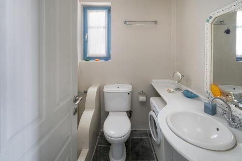 a white bathroom with a toilet and a sink at Almira 2 in Livadakia