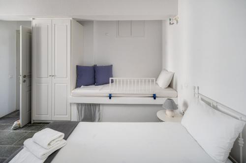 a white bedroom with a bed and a bench at Almira 2 in Livadakia