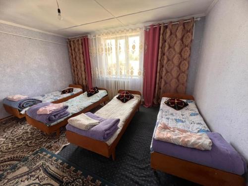 a room with three beds and a window at Temirbek Guest House in Jangy-Talap