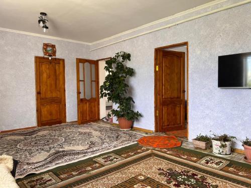 a living room with wooden doors and a tv on a wall at Temirbek Guest House in Jangy-Talap