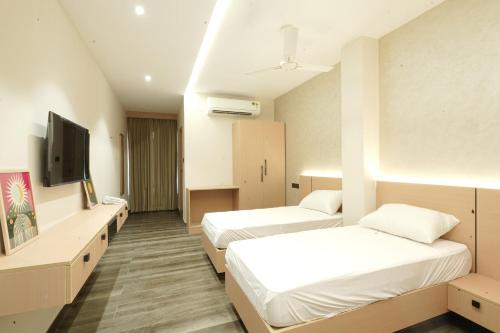 a hotel room with two beds and a flat screen tv at Rest and Rise Inn in Bhīmavaram