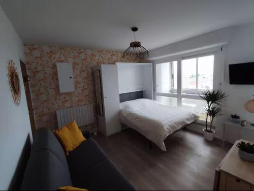 a bedroom with a bed and a couch in a room at Vue Mer sur Juno Beach - Studio in Courseulles-sur-Mer