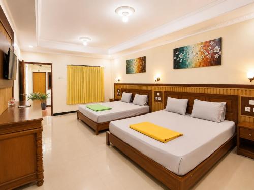 a bedroom with two beds and a television at Satya Graha Hotel Yogyakarta in Yogyakarta