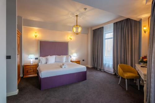 a hotel room with a large bed and a desk at Phoenicia Grand Hotel in Bucharest