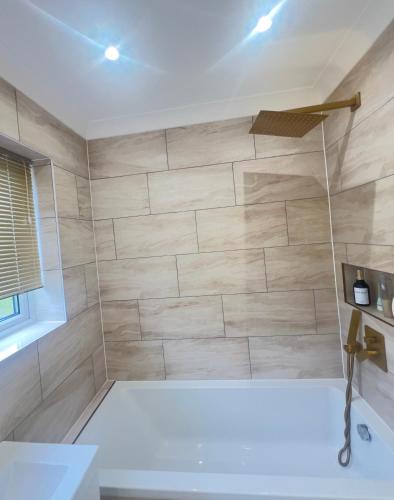 a bathroom with a shower with a white tub at The Stanford Home in Horndon on the Hill