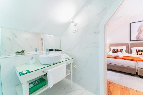 a white bathroom with a sink and a bed at A&S Suítes Coimbra in Coimbra