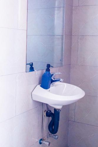 a bathroom sink with a blue bottle on it at WN Apartments in Lusaka