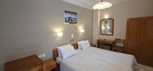 a bedroom with a bed and a table and a mirror at Hotel Adonis in Mythimna