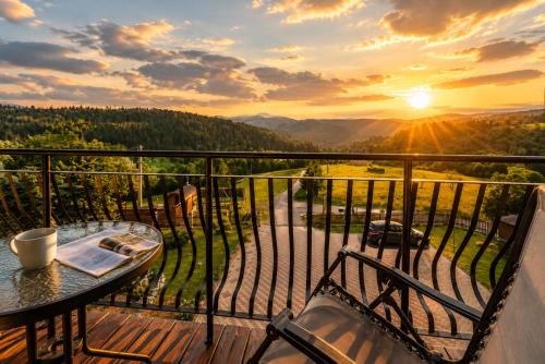 a balcony with a table and chairs and the sunset at Apartamenty Pod Horodkiem in Cisna