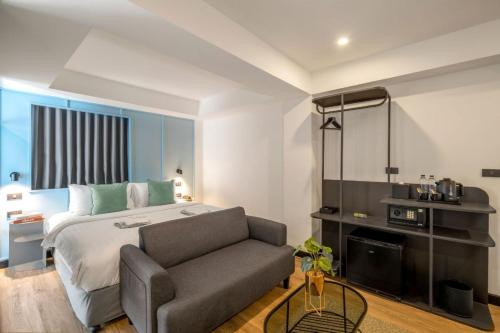 a bedroom with a bed and a couch at CMYK Boutique Hotel in Bangkok