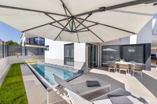 a patio with an umbrella and a swimming pool at Villa Sarah in Vantačići