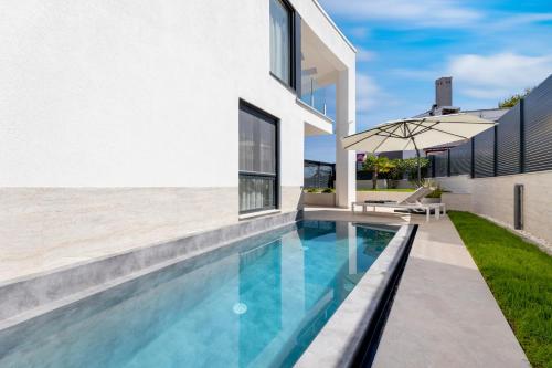 a swimming pool with an umbrella next to a house at Villa Sarah in Vantačići