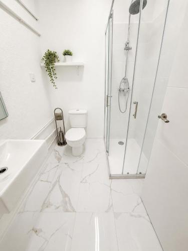 a white bathroom with a shower and a toilet at Apartamento con piscina cerca de Barcelona in El Masnou
