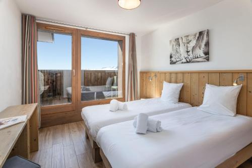 two beds in a room with a large window at Residence Le Roc Noir by Alpapart in La Rosière
