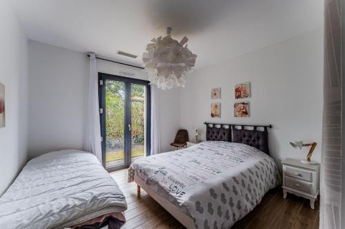 a bedroom with two beds and a chandelier at Le Reve Mimizan Plage in Mimizan-Plage