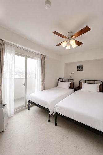 two beds in a bedroom with a ceiling fan at O2 capsule house OTARU in Otaru