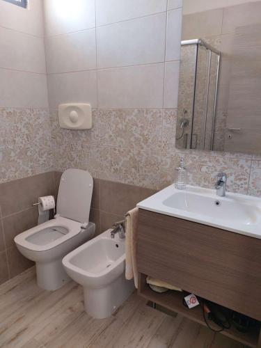 a bathroom with a toilet and a sink and a mirror at Domus Vida in Quartu Sant'Elena