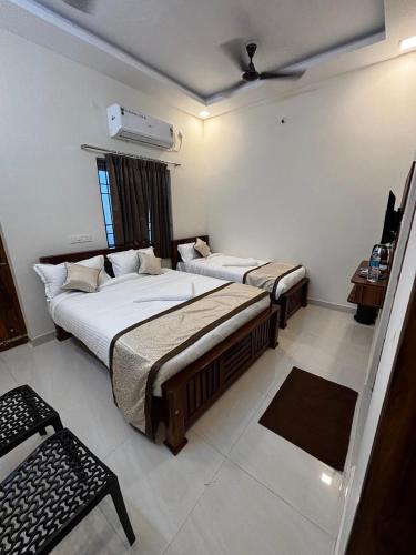 a bedroom with two beds and a window at Sai Meridian in Pondicherry