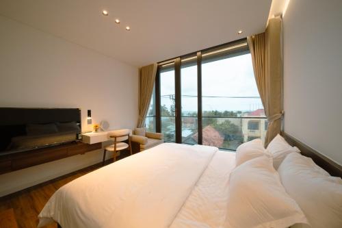 a bedroom with a large white bed with a large window at ANNA Boutique Villa - Sea View in Phan Thiet