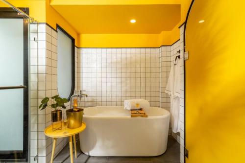a bath tub in a bathroom with a yellow ceiling at CMYK Boutique Hotel in Bangkok