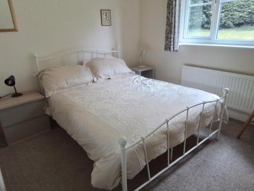 a white bed in a bedroom with a window at Elderflower Cottage in Stamford