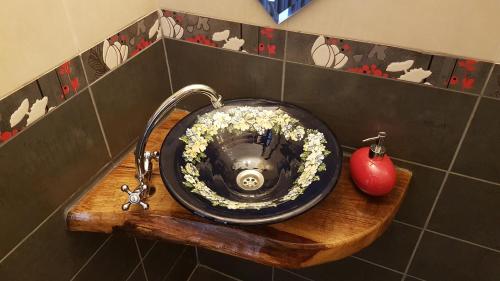 a bathroom with a sink with flowers and an apple at Pensiunea Agroturistica Cerna, Vaideeni - Polovragi in Vaideeni