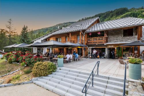 a building with stairs and people sitting outside of it at Hôtel et Camping O2 Orcières Outdoor Area in Orcières