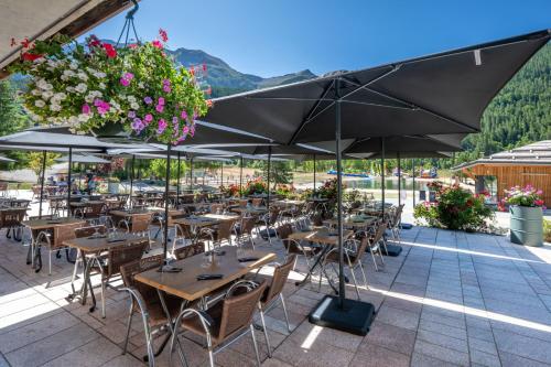 a restaurant with tables and chairs and umbrellas at Hôtel et Camping O2 Orcières Outdoor Area in Orcières