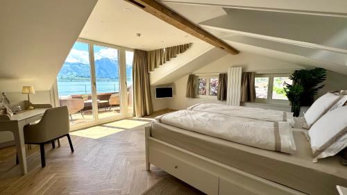 a bedroom with a large bed and a desk with a desk at Boutique Hotel Niesenblick - direkt am Thunersee gelegen mit SELF CHECK IN & digitaler Rezeption in Oberhofen am Thunersee
