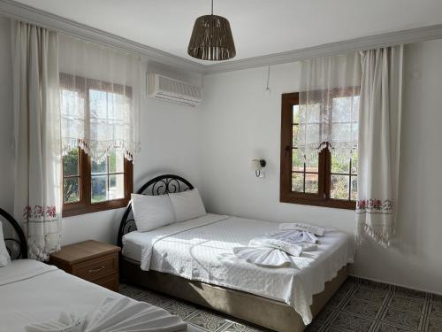 a bedroom with two beds and two windows at Melinda Pension & Restaurant in Mesudiye