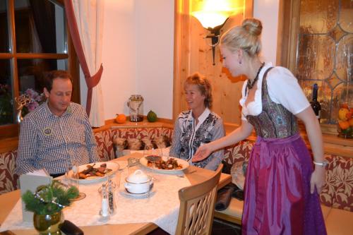 a woman standing in front of a table with food at Hotel und Alpen Apartments mit Sauna - Bürglhöh in Bischofshofen