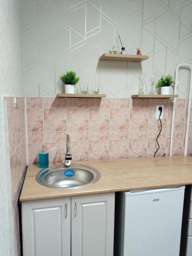 a bathroom with a sink and a pink tiled wall at Строитель 39 in Oral