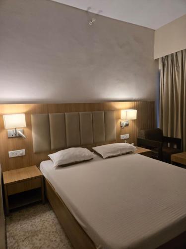 a bedroom with a large bed with two lamps at Atithi Palace in Bhāgalpur