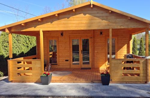 a wooden gazebo with a roof and glass doors at Zacisze domek z Jacuzzi & Sauna in Chrołowice