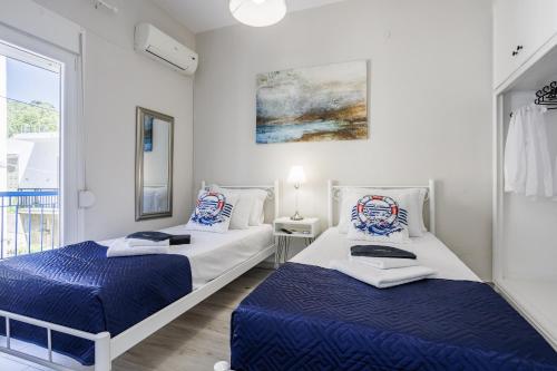 two beds in a white room with blue sheets at Andromachi's house in Loutraki