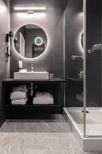 a bathroom with a sink and a mirror and a tub at Hotel Krynica Conference & SPA in Krynica Zdrój