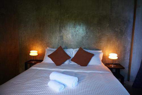 a bedroom with a bed with two pillows and two lamps at yolked suites in General Luna