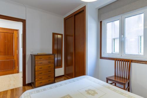 a bedroom with a bed and a dresser and a window at Apartamento Río do Con Vilagarcía in Vilagarcia de Arousa