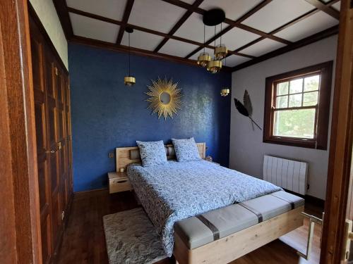 a bedroom with a bed with a blue wall at Le rêve au fil de l'eau in Marmagne